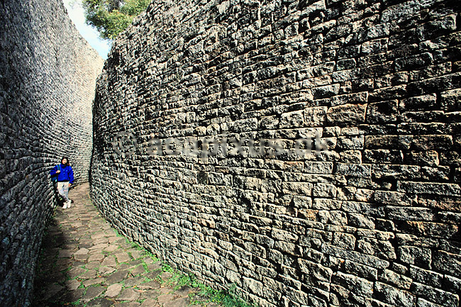 Great Zimbabwe. Great Zimbabwe, Great Enclosure - Turist imellem inder- og ydermur - Ordet Zimbabwe betyder stenhus p� shona. ( Scan af KOL3604 ) ; ; Great Zimbabwe / Masvingo; Zimbabwe; Afrika; ; Zimbabwe er opkaldt efter ruinerne