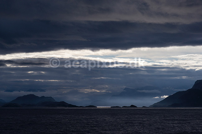 Gr�nland. Gr�nlands kyst set fra kystf�rgen mellem Ililissat og Nuuk. Solen skinner ned mellem skyer p� havets overflade; ; ; Gr�nland; ; ; 