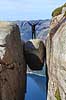 Kjeragbolten. Fjeldvandrer p� Kjeragbolten, en stor sten klemt fast imellem to klippesider 1000 meter (ja) over Lysefjord  Kjerag / Stavanger Norge   Vandring, vandretur, fjeldvandring, turisme, hiking