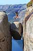 Kjeragbolten. Fjeldvandrer p� Kjeragbolten, en stor sten klemt fast imellem to klippesider 1000 meter (ja) over Lysefjord  Kjerag / Stavanger Norge   Vandring, vandretur, fjeldvandring, turisme, hiking