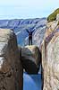 Kjeragbolten. Fjeldvandrer p� Kjeragbolten, en stor sten klemt fast imellem to klippesider 1000 meter (ja) over Lysefjord  Kjerag / Stavanger Norge   Vandring, vandretur, fjeldvandring, turisme, hiking