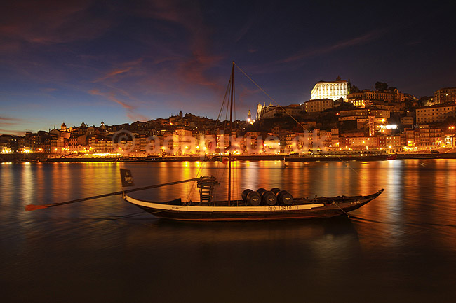 Porto i aftenskumring. Duoro floden og den gamle bydel Ribeira i Porto - i forgrunden en rabelo b�d med portvinst�nder - rabelo b�dene anvendtes tidligere til at transportere portvin p� Duoro floden, men er idag kun en udsmykning p� floden; ; Porto; Portugal; ; ; Bybilleder, floder