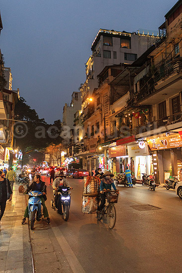 Hanoi. Cyklist cykler med sin tungt lastede cykel mellem scootere og biler i aftentrafikken i Hanoi; ; Hanoi; Vietnam; ; ; Trafik, scootere, kaos